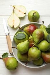 Photo of Fresh ripe pears, knife and green leaves on white wooden table, flat lay