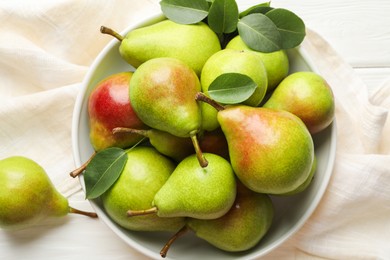 Photo of Fresh ripe pears in bowl and green leaves on white wooden table, top view