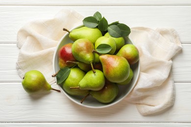 Photo of Fresh ripe pears in bowl and green leaves on white wooden table, top view