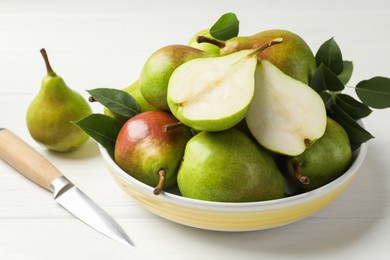 Photo of Fresh ripe pears, knife and green leaves on white wooden table, closeup