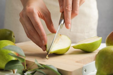 Photo of Woman cutting fresh ripe pear at table, closeup