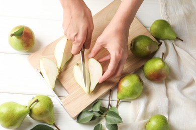 Photo of Woman cutting fresh ripe pear at white wooden table, top view