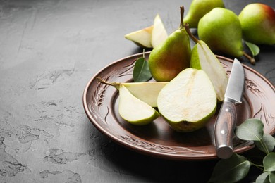 Photo of Fresh ripe pears, knife and green leaves on black table, closeup. Space for text