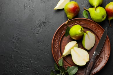 Photo of Fresh ripe pears, knife and green leaves on black table, flat lay. Space for text