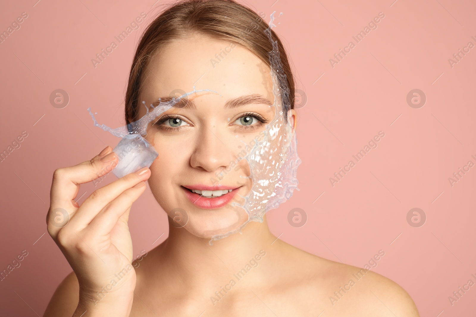 Young woman with ice cube and water splashes on pink beige background Image of Young woman with ice cube and water splashes on pink beige background