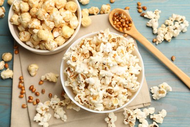 Photo of Tasty popcorn and corn kernels on light blue wooden table, flat lay