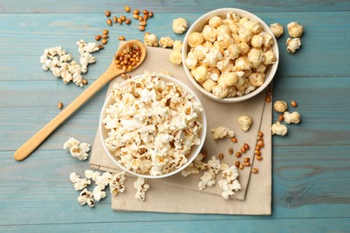 Photo of Tasty popcorn and corn kernels on light blue wooden table, flat lay