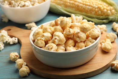 Photo of Tasty popcorn and corncob on light blue wooden table, closeup