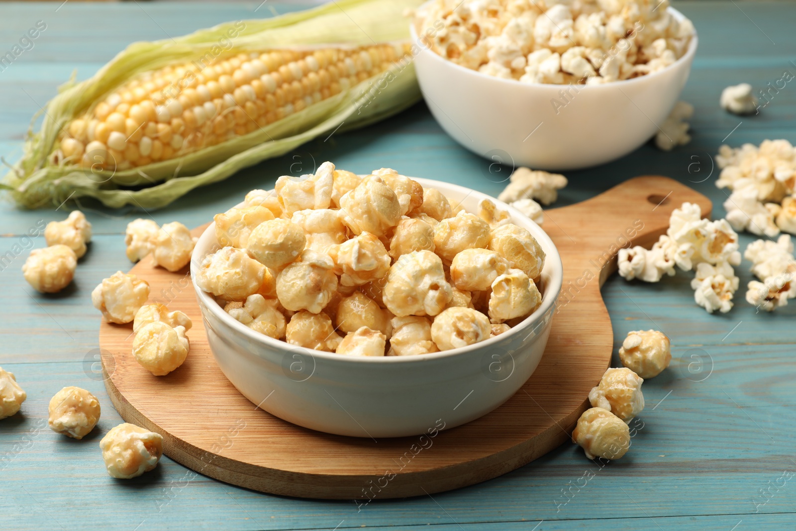 Photo of Tasty popcorn and corncob on light blue wooden table, closeup