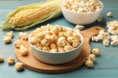 Photo of Tasty popcorn and corncob on light blue wooden table, closeup