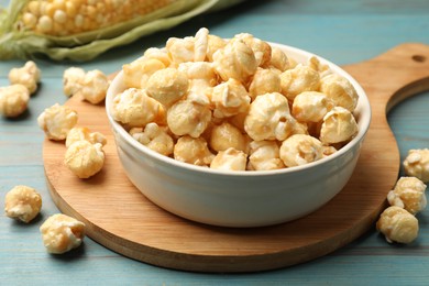 Photo of Tasty popcorn and corncob on light blue wooden table, closeup
