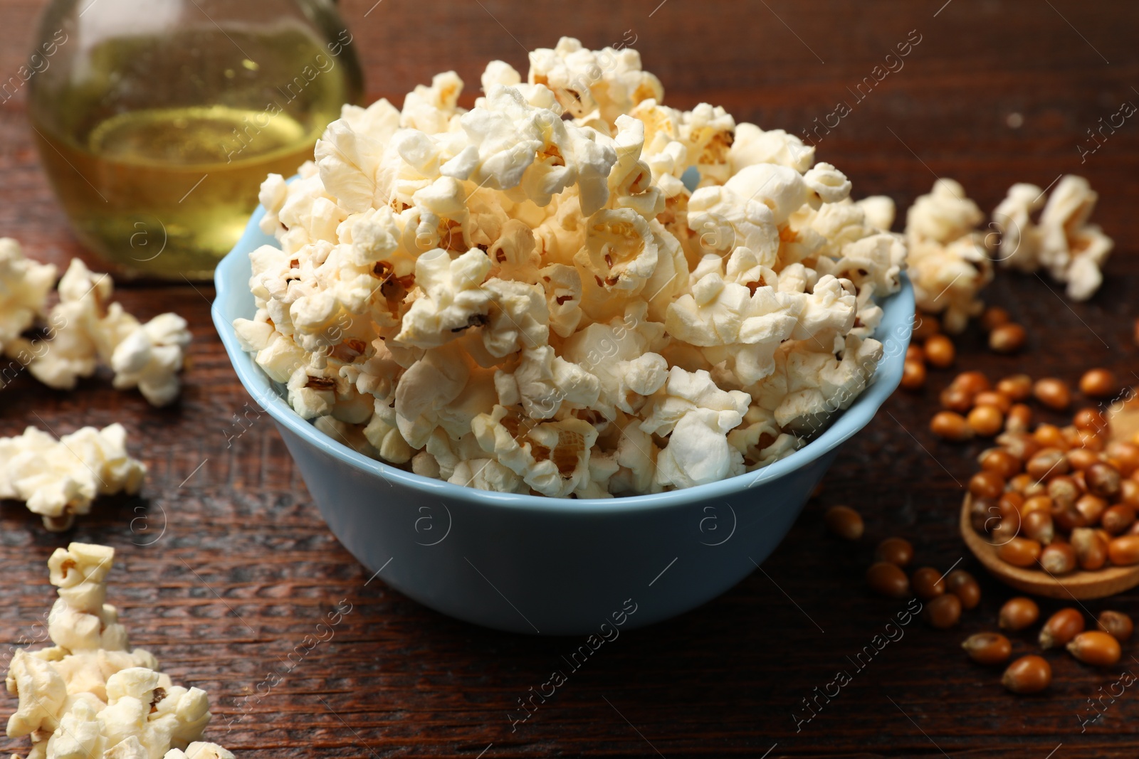 Tasty popcorn, oil and corn kernels on wooden table, closeup Photo of Tasty popcorn, oil and corn kernels on wooden table, closeup