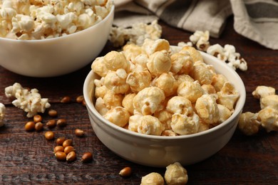 Photo of Tasty popcorn and corn kernels on wooden table, closeup
