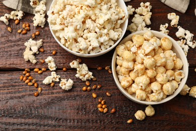 Photo of Tasty popcorn and corn kernels on wooden table, flat lay