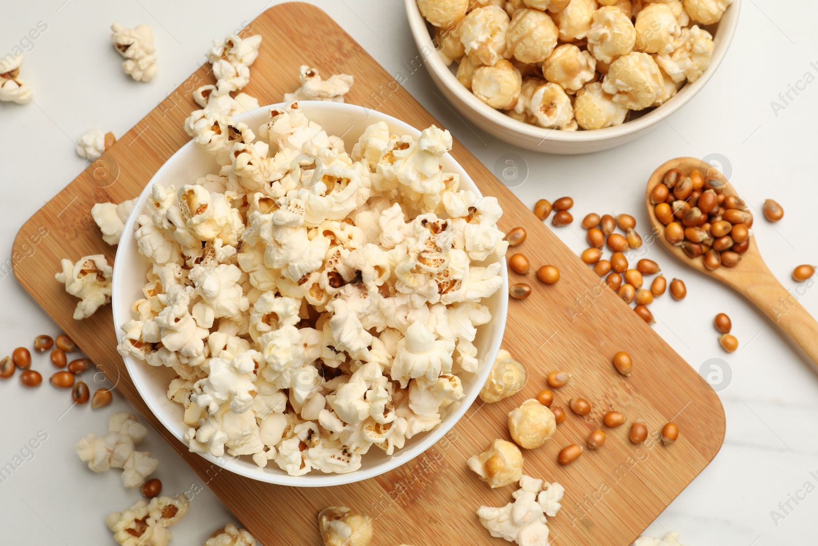 Tasty popcorn and corn kernels on white marble table, flat lay Photo of Tasty popcorn and corn kernels on white marble table, flat lay