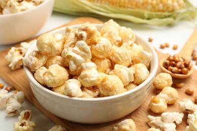 Photo of Tasty popcorn, corncob and corn kernels on white table, closeup