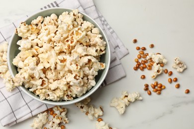 Photo of Tasty popcorn and corn kernels on white marble table, flat lay