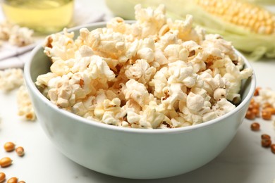 Photo of Tasty popcorn and corn kernels on white marble table, closeup