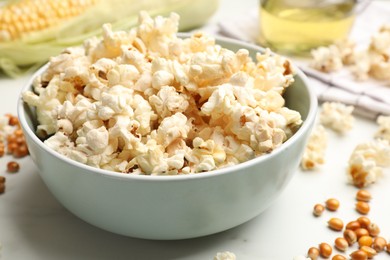 Photo of Tasty popcorn and corn kernels on white marble table, closeup