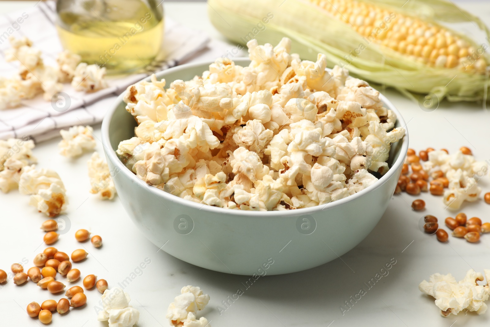 Tasty popcorn and corn kernels on white marble table, closeup Photo of Tasty popcorn and corn kernels on white marble table, closeup
