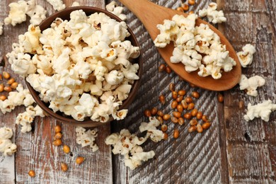 Photo of Tasty popcorn and corn kernels on wooden table, flat lay