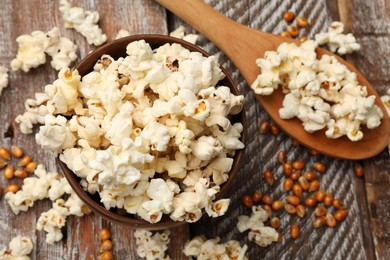 Photo of Tasty popcorn and corn kernels on wooden table, flat lay