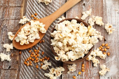 Photo of Tasty popcorn and corn kernels on wooden table, flat lay