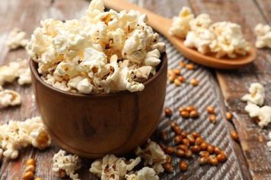 Photo of Tasty popcorn and corn kernels on wooden table, closeup