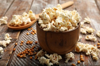 Photo of Tasty popcorn and corn kernels on wooden table, closeup