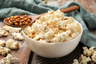 Photo of Tasty popcorn and corn kernels on wooden table, closeup