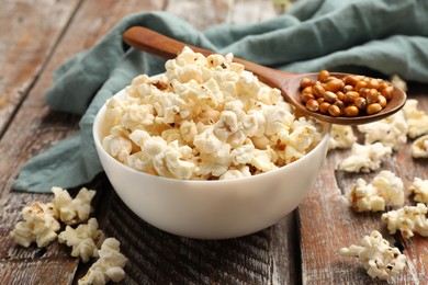 Photo of Tasty popcorn and corn kernels on wooden table, closeup