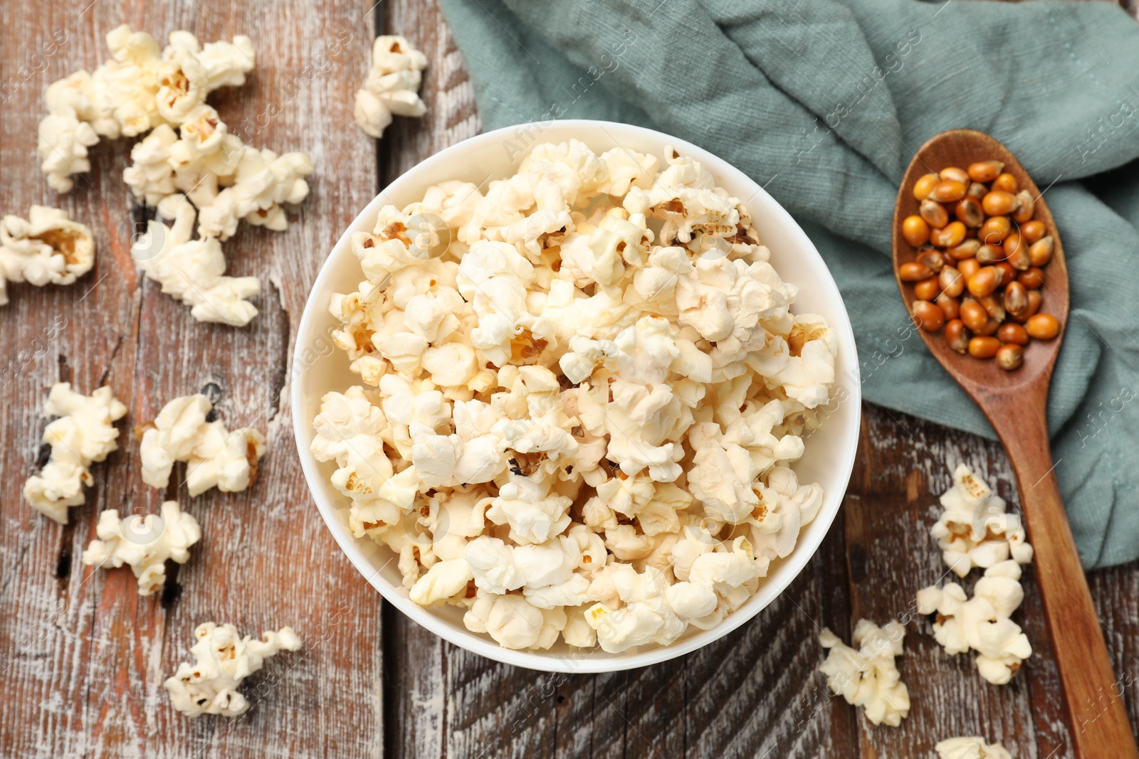 Photo of Tasty popcorn and corn kernels on wooden table, flat lay