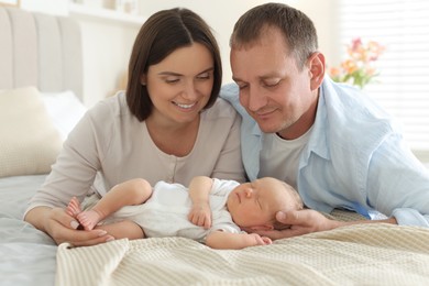 Photo of Mom and dad with their newborn baby on bed at home