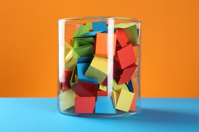 Photo of Bright paper pieces in glass jar on color background