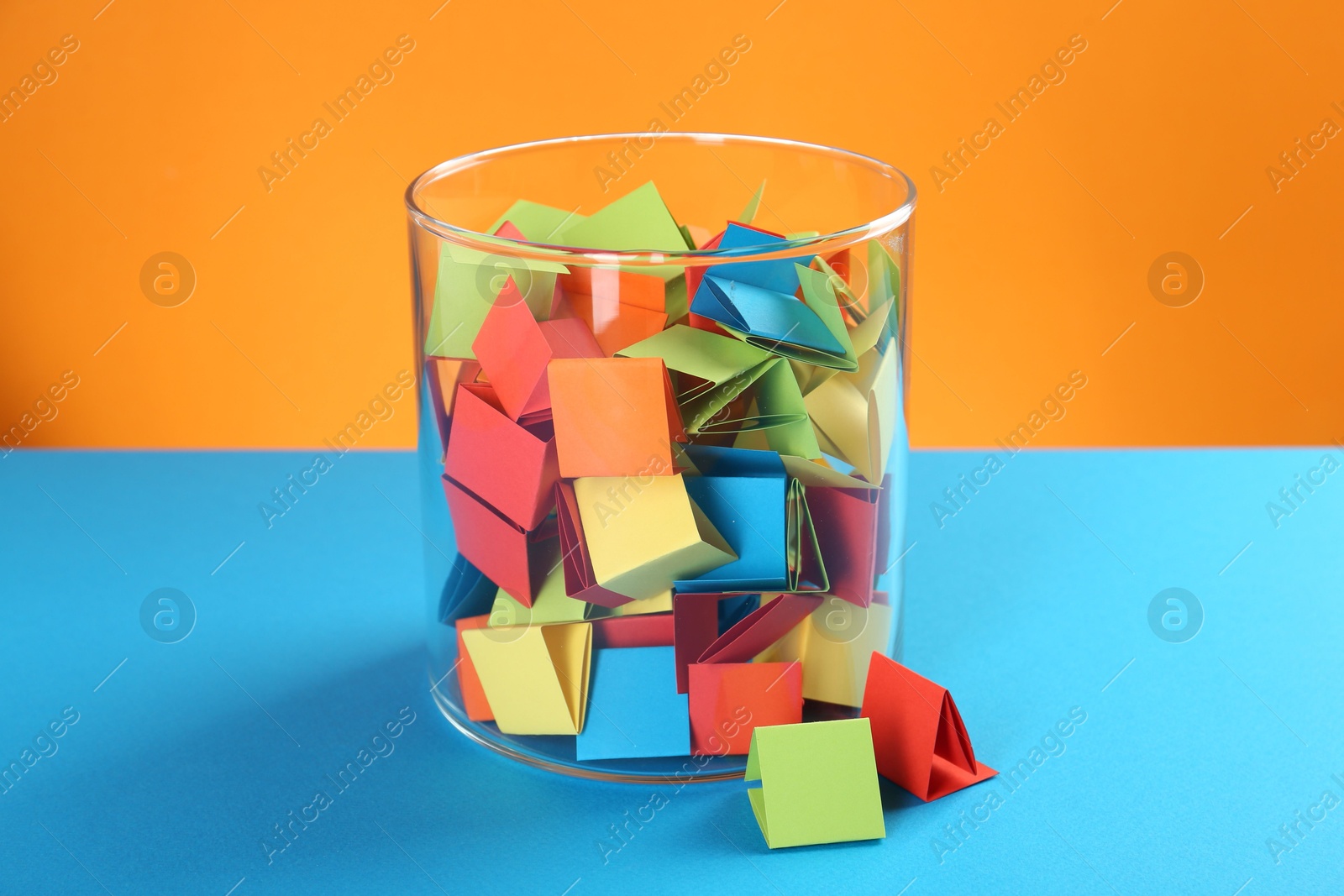 Bright paper pieces in glass jar on color background Photo of Bright paper pieces in glass jar on color background