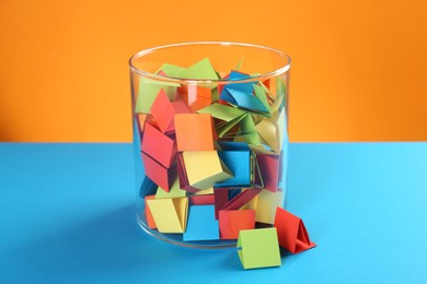Photo of Bright paper pieces in glass jar on color background