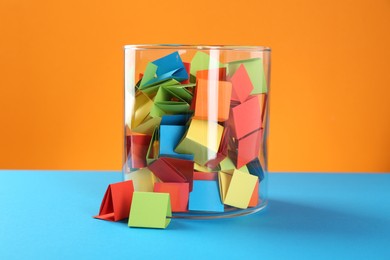 Photo of Bright paper pieces in glass jar on color background