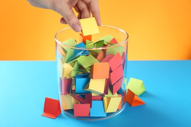 Photo of Woman taking yellow paper piece from glass jar on color background, closeup