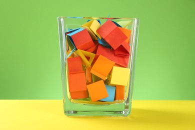 Photo of Bright paper pieces in glass jar on color background