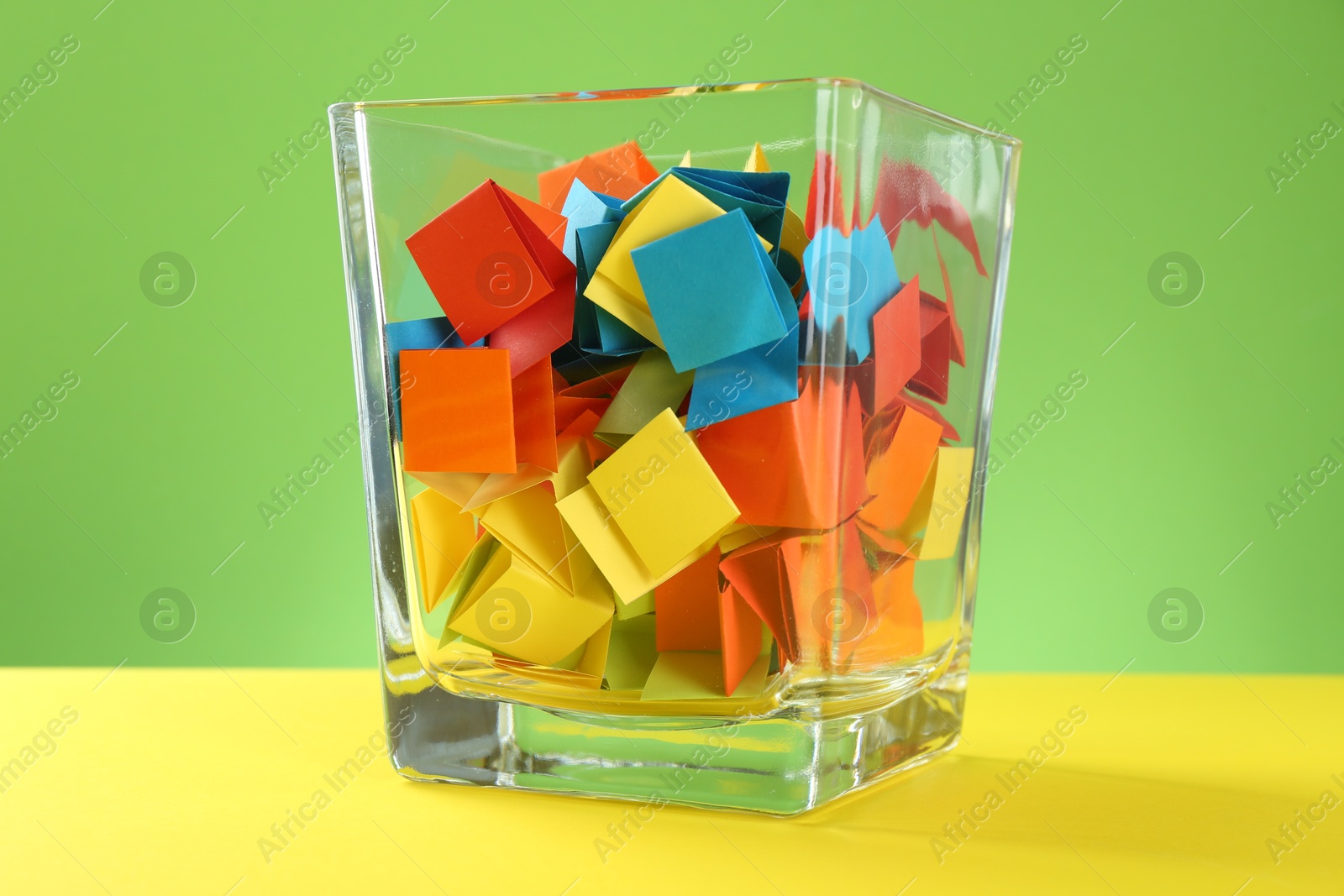 Bright paper pieces in glass jar on color background, closeup Photo of Bright paper pieces in glass jar on color background, closeup