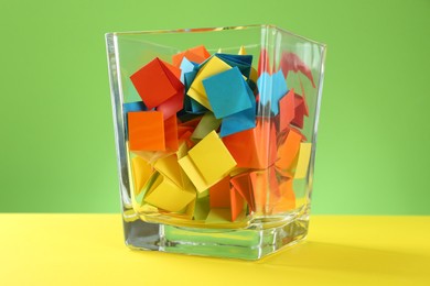 Photo of Bright paper pieces in glass jar on color background, closeup