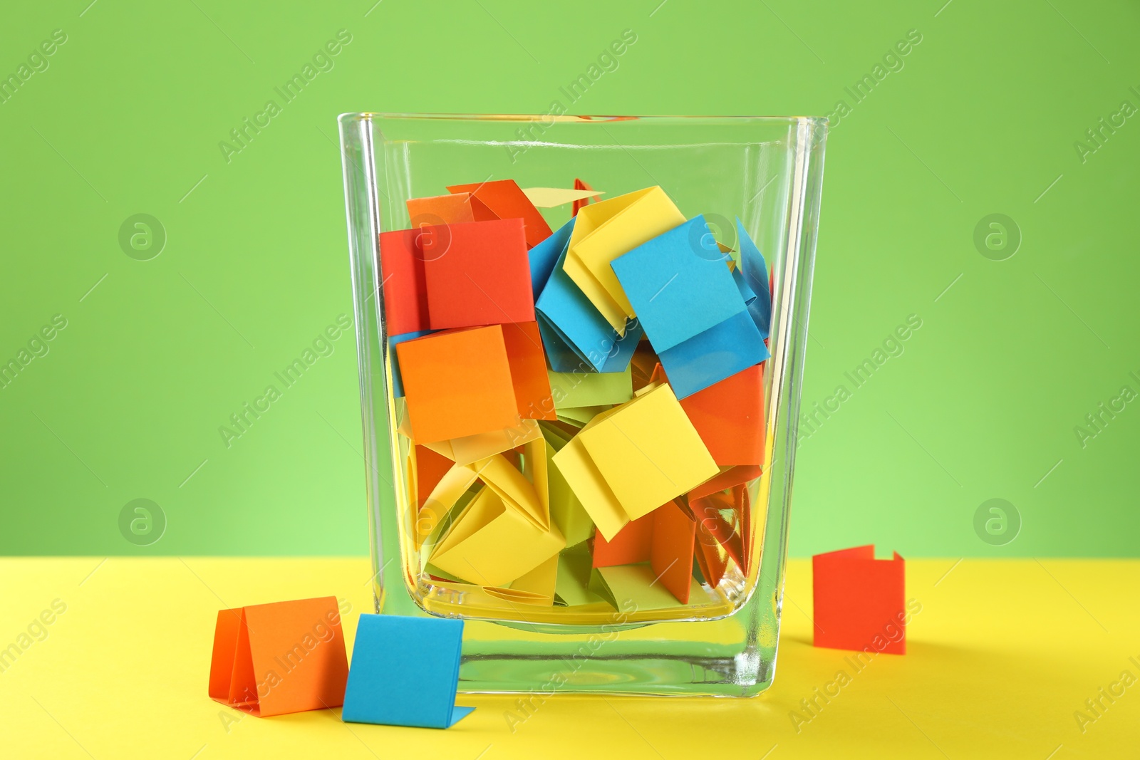Bright paper pieces in glass jar on color background Photo of Bright paper pieces in glass jar on color background