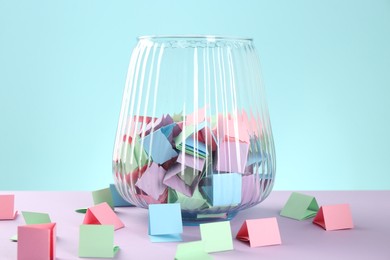 Photo of Bright paper pieces in glass jar on color background, closeup