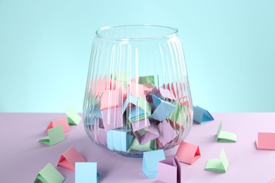 Photo of Bright paper pieces in glass jar on color background, closeup