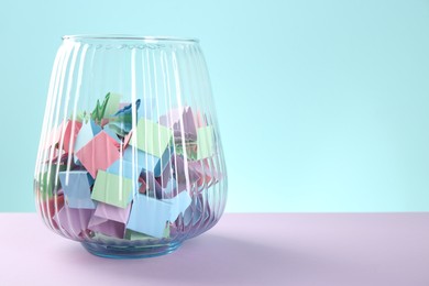 Photo of Bright paper pieces in glass jar on color background, closeup. Space for text