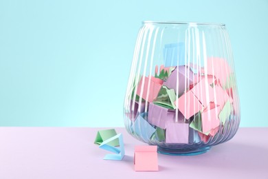 Photo of Bright paper pieces in glass jar on color background. Space for text