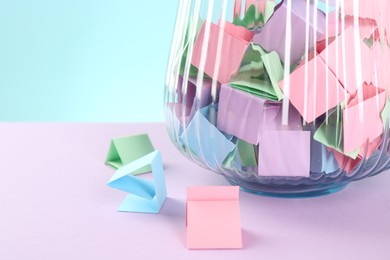 Photo of Bright paper pieces in glass jar on color background, closeup. Space for text