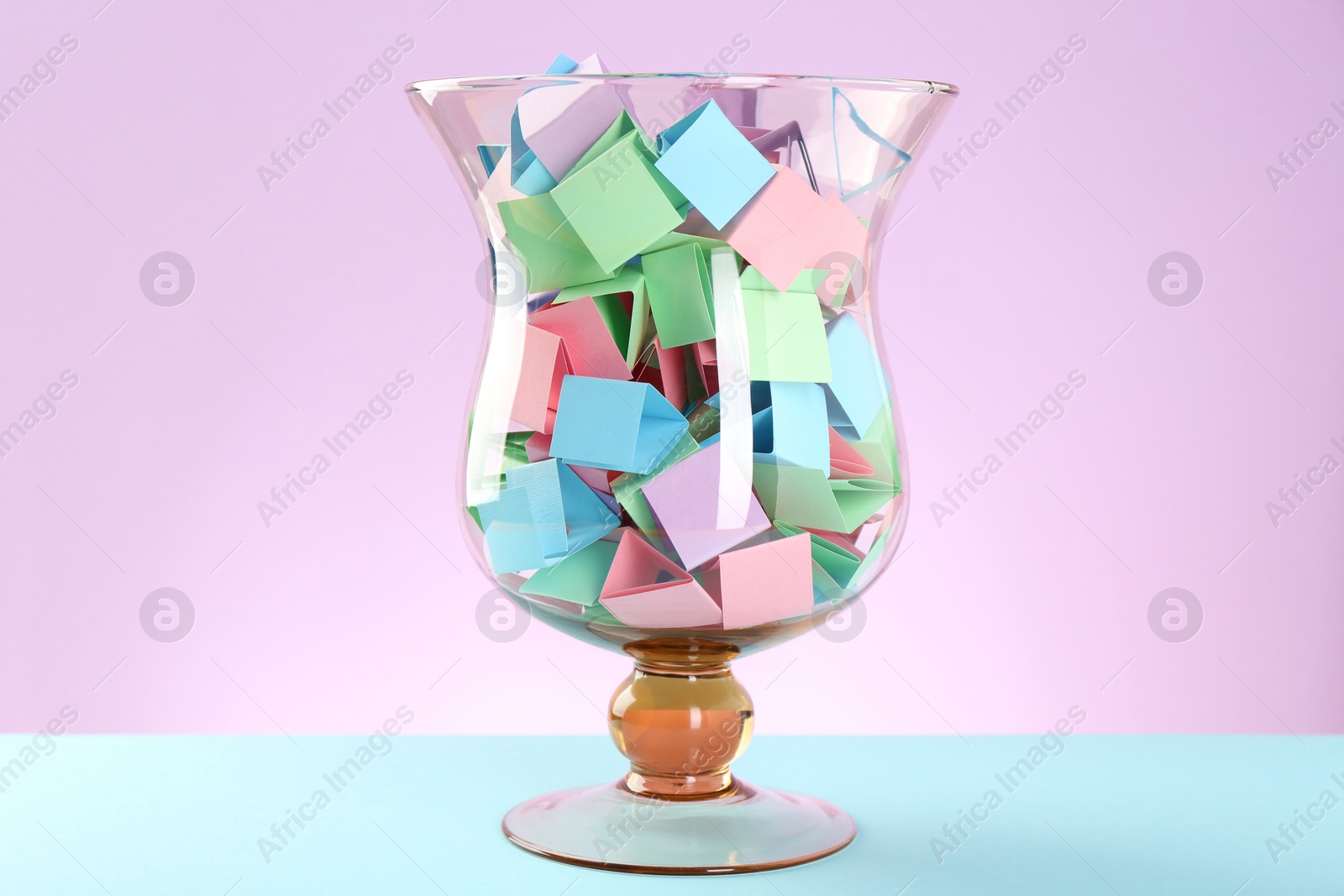 Bright paper pieces in glass jar on color background Photo of Bright paper pieces in glass jar on color background