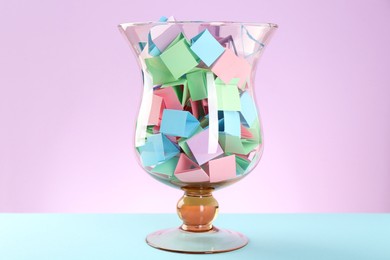 Photo of Bright paper pieces in glass jar on color background