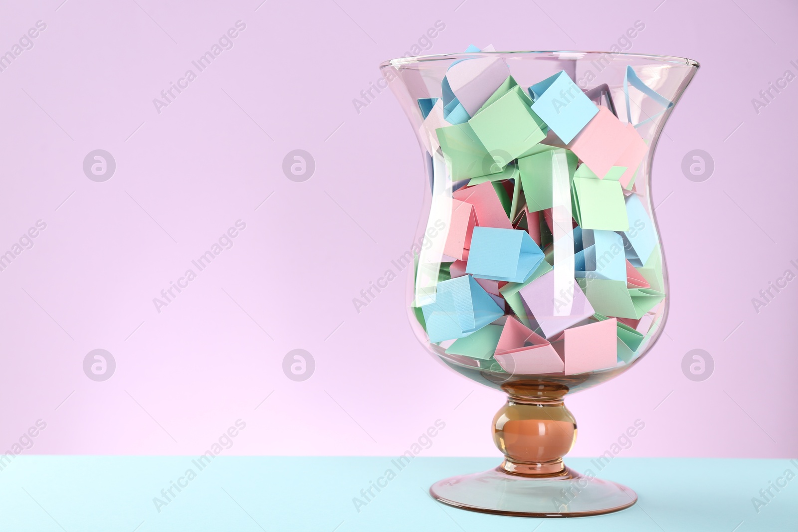 Bright paper pieces in glass jar on color background. Space for text Photo of Bright paper pieces in glass jar on color background. Space for text